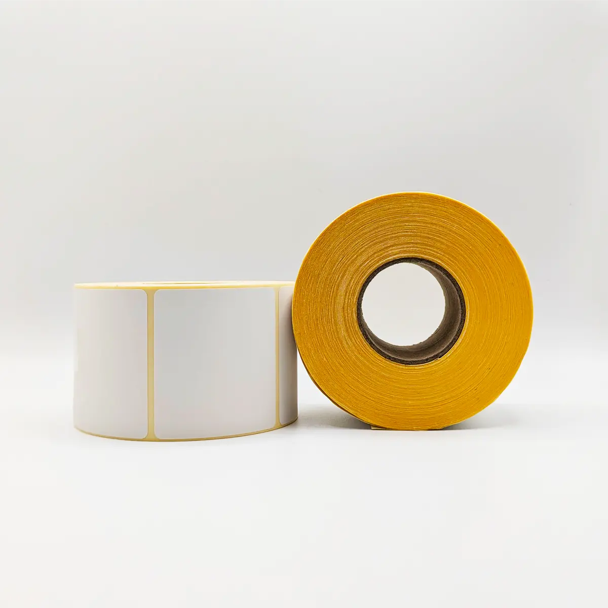 Etikettenrolle mit 58 x 53 mm Etiketten auf gelbem Trägerpapier von der Seite  mit Stapel